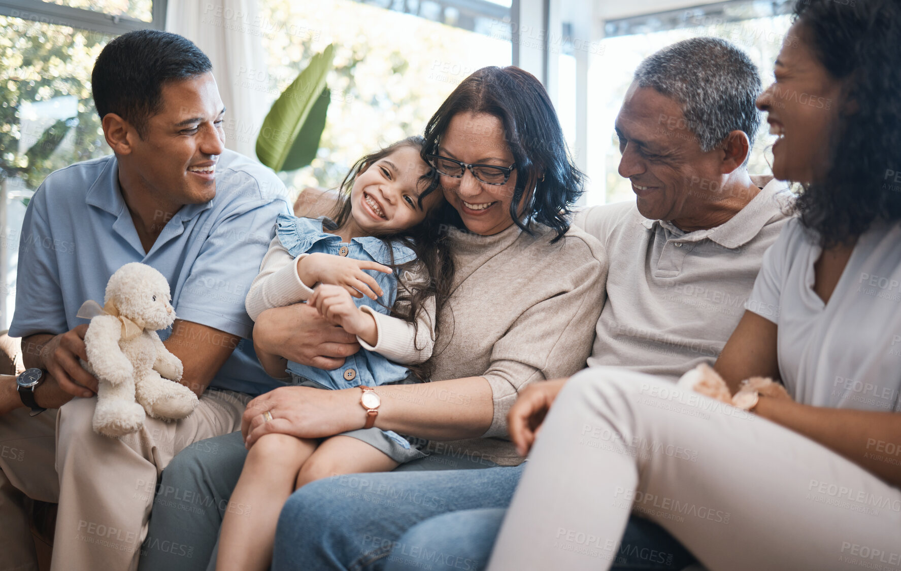 Buy stock photo Big family, parents and girl with teddy bear on sofa, grandparents and tickle for game in home living room. Men, women and female child with toys, love and bonding on lounge couch in house on holiday