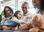 Love, kids and teddy bear with a family on the sofa in the living room of their home together during a visit. Parents, grandparents and children in the lounge of a house for bonding or relaxing