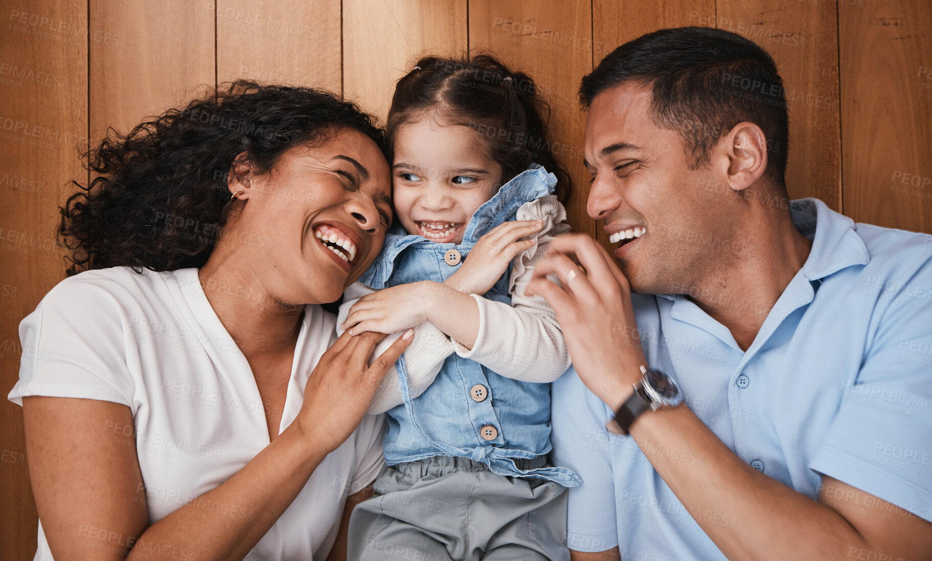 Buy stock photo Love, funny and family with girl, parents and hug with bonding, quality time and happiness. Mother, happy father and daughter with dad, mama and female child embrace, laughing and support at home