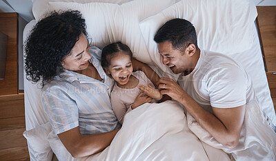 Buy stock photo Mom, dad and child tickle in a bedroom bed in the morning at family home with bonding. Laughing, mother and father with a young girl being playful and happy with a smile and youth together with love