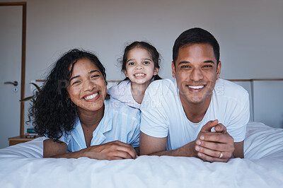Buy stock photo Bonding, love and portrait of a family in a bedroom in their relaxing, spending quality time and bonding together. Happy, smile and girl child laying on a bed with her parents in their modern home.