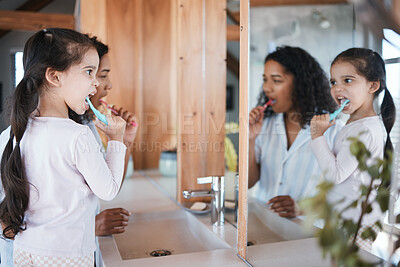 Buy stock photo Brushing teeth, girl and mom with dental cleaning and mirror in a bathroom. Mother, kid and smile of wellbeing and wellness with learning of health care and toothbrush in the morning at home