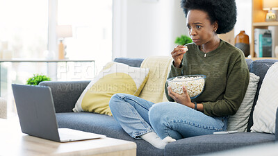 Buy stock photo Black woman, watching and movie on a laptop eating popcorn on a living room couch. Scared female person, home lounge and online series with film snack and food with video on computer in a house