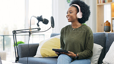 Cool journalist using digital tablet, talking into microphone and hosting podcast or broadcasting news while wearing headphones. Excited young woman using technology to promote on air from home