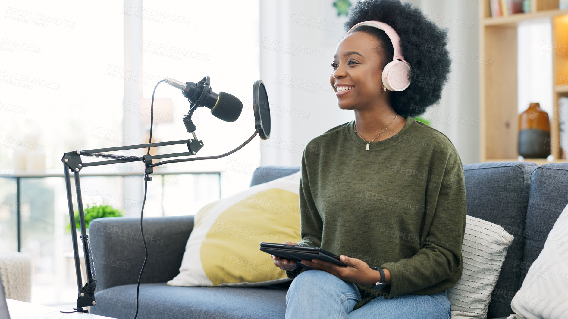 Buy stock photo Headphones, tablet and black woman on microphone in podcast at home in living room of influencer. Technology, smile and content creator on mic for live broadcast, recording audio and radio on sofa