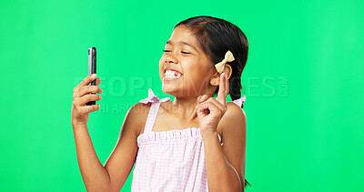 Child, peace and smile for selfie on green screen background for happiness and motivation in studio. Face of happy girl kid with technology for profile picture of connection with hand sign or emoji
