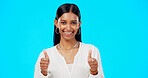 Thumbs up, excited and success by woman with hand gesture for approval isolated in studio blue background. Emoji, face and portrait of Indian female with fashion, perfection and support review