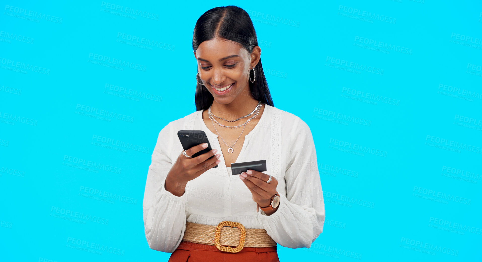 Buy stock photo Happy woman in studio with phone, credit card and online shopping, banking or payment. Ecommerce, financial freedom and girl with smile on smartphone app for cashback or search on blue background.