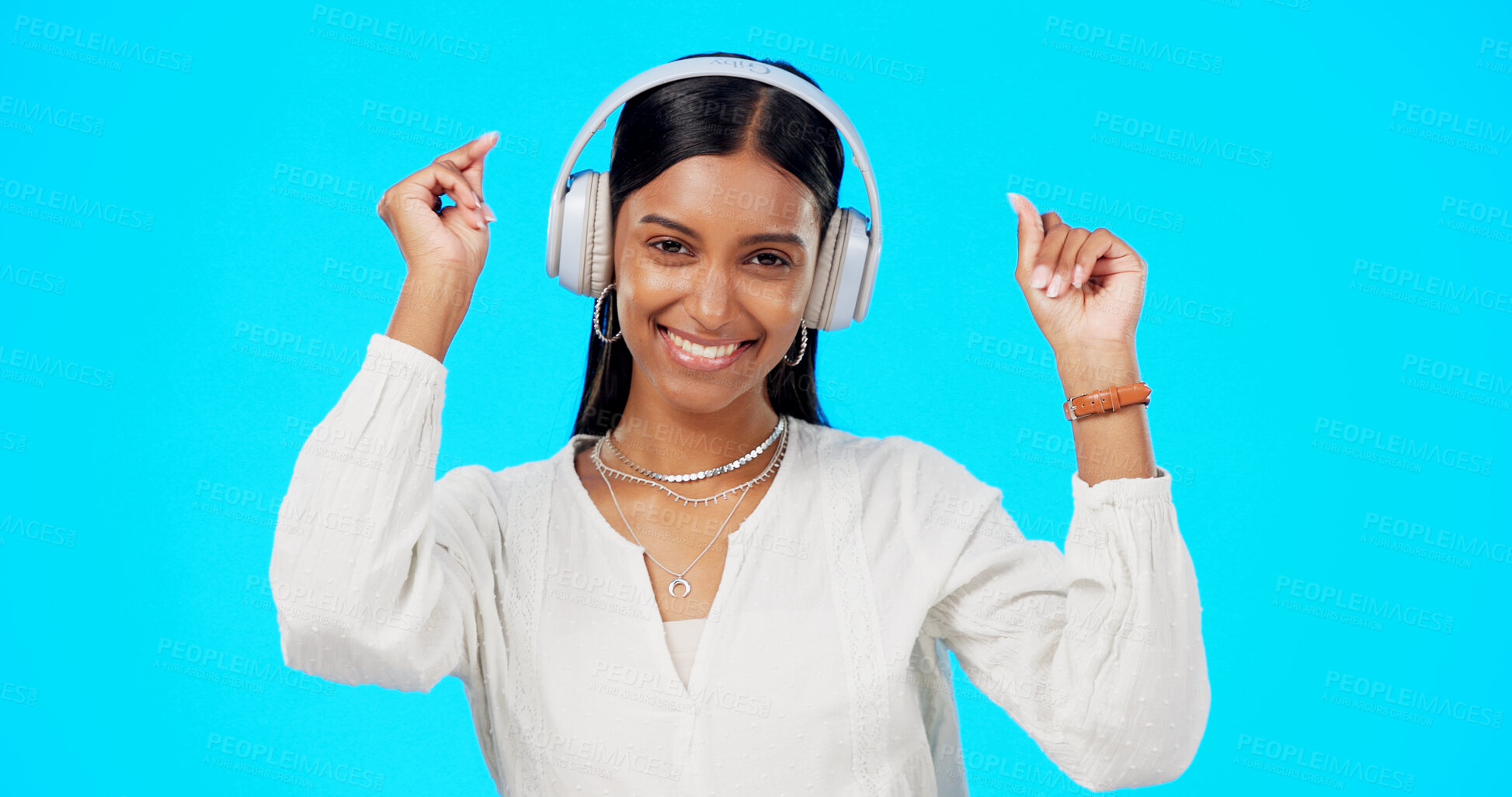 Buy stock photo Dance, portrait of woman and headphones in studio to celebrate party, freedom and hearing audio on blue background. Happy indian model listening to multimedia, music or radio subscription with energy
