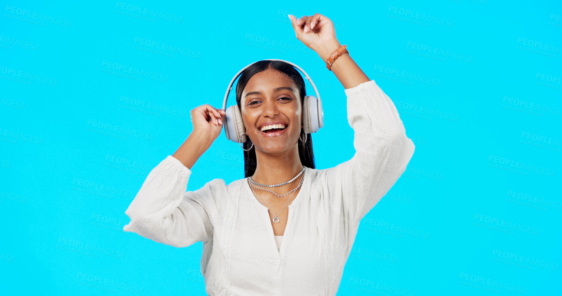 Buy stock photo Dancing, headphones or portrait of happy woman in studio to celebrate party, freedom or hearing audio on blue background. Indian model listening to multimedia, music or radio subscription with energy