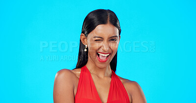 Buy stock photo Happy, wink and young woman in a studio for valentines day or anniversary flirting emoji. Excited, romance and portrait of Indian female model with fun personality isolated by a blue background.