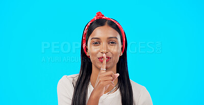Secret, face and happy woman with finger on lips in studio, blue background and privacy sign. Portrait, indian model and shush for quiet, gossip and whisper of confidential mystery, emoji and smile