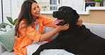 Happy woman relax with her dog on sofa for mental health, wellness or emotional support, love and care. Young person relaxing on living room couch and stroking puppy pet, animal or Labrador retriever