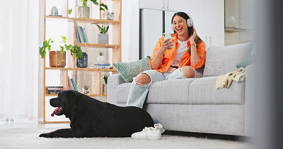 Phone, headphones and laughing woman with dog on sofa in home living room. Comic, relax and happy female streaming music, radio or podcast with smartphone while playing with animal, pet or bonding.