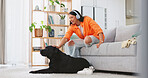 Phone, headphones and laughing woman with dog on sofa in home living room. Comic, relax and happy female streaming music, radio or podcast with smartphone while playing with animal, pet or bonding.