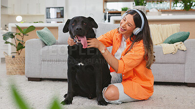 Headphones, dog petting and woman in a living room feeling puppy love from pet care in a home. House, animal and young female listening to music with happiness and bonding from labrador attention