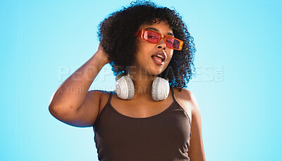 Face wink, sunglasses and hair care of woman in studio isolated on a blue background. Gen z portrait, retro shades and happy mixed race female model with salon treatment for beauty and headphones.