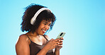 Black woman, phone and headphones isolated on blue background listening to music, social media video or funny meme. Happy gen z person laughing for audio tech, internet post and cellphone in studio