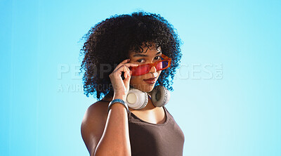 Face, sunglasses and beauty of woman in studio isolated on a blue background. Fashion portrait, smile shades and happy mixed race female model with trendy, stylish or retro, cool or gen z headphones.