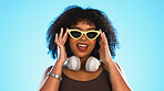 Trendy black woman face isolated on blue background for beauty, cosmetics and fashion of gen z lifestyle. Confident african american person or model with cool sunglasses and headphones for summer