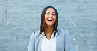 Cheerful woman laughing and giggling about something funny while standing outside against a grey wall with copy space. Happy businesswoman having fun and expressing positivity and a playful attitude