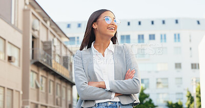 Happy business woman looking away, thinking about career possibilities or opportunities, smiling and laughing while standing arms crossed in the city. A young corporate professional feeling positive