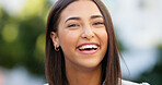 Portrait of a beautiful girl standing and commuting in the city. One happy and stylish young female smiling and relaxing downtown. Trendy young woman showing her teeth, laughing and traveling in town