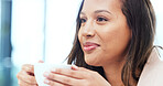 Woman drinking a hot cup of tea or coffee at home. Face of a carefree young female smelling the aroma of a fresh warm beverage while taking a sip and relaxing at home. Enjoying a comfortable break