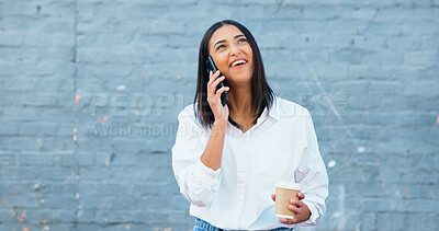 A stylish female journalist student talking on the phone outside a wall with copy space. Young confident woman enjoying a call conversation outdoors while having her morning cup of coffee