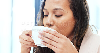 Woman drinking a hot cup of tea or coffee at home. Face of a carefree young female smelling the aroma of a fresh warm beverage while taking a sip and relaxing at home. Enjoying a comfortable break