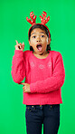 Christmas, antlers and idea with a girl on a green screen background in studio looking surprised. Children, portrait and eureka with an adorable little female child having an aha moment on chromakey