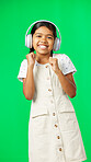 Children, music and dance with a girl on a green screen background in studio streaming audio. Portrait, smile and fun with an adorable little girl dancing while listening to the radio on headphones