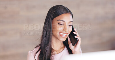Secretary talking on a phone while working on a computer at a front desk. Cheerful young receptionist with a friendly tone scheduling appointments and confirming meetings with clients in an office
