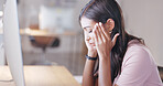 Woman suffering from a headache or migraine while working on desktop computer in an office at work. Upset and stressed female massaging her head while working overtime and trying to meet a deadline