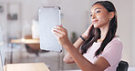 Young happy woman taking a selfie with a digital tablet while relaxing in an office at work. One smiling female student taking pictures to post on social media while sitting alone in a library