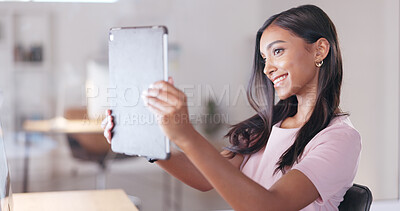 Young happy woman taking a selfie with a digital tablet while relaxing in an office at work. One smiling female student taking pictures to post on social media while sitting alone in a library