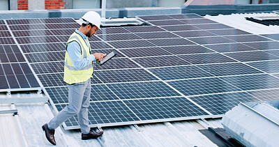 Electrician checking solar panels technology on the roof of the building his working on. Professional engineer technician wearing a safety helmet looks closely at his modern renewable energy design