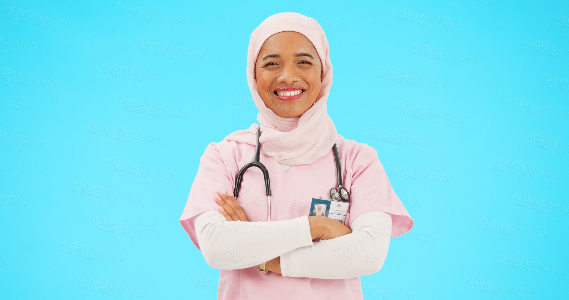 Buy stock photo Muslim woman, face and nurse smile with arms crossed, proud and healthcare on a blue studio background. Portrait, happy Islamic person or medical professional with confidence, career and mockup space