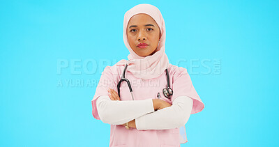 Buy stock photo Muslim woman, arms crossed and doctor in studio portrait for wellness, care and career by blue background. Islamic person, nurse and hijab for religion at job for healthcare, consulting and help