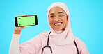Phone, green screen and doctor woman isolated on blue background for healthcare tracking marker and mockup space. Face of nurse or muslim person with medical mobile app for advertising in studio