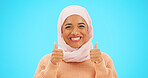 Muslim woman, happy and thumbs up portrait in studio for mockup, advertising or promotion. Islamic female with hand emoji, smile and hijab excited for announcement or sale on blue background