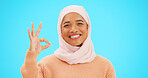 Muslim woman, ok sign and smile on face with hand for emoji, icon or agreement. Islamic female with hijab and symbol for thank you, support and agreement or approval on a studio blue background