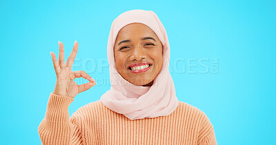 Buy stock photo Muslim woman, ok sign and smile in studio portrait, review and good service by blue background. Islamic person, girl and hijab emoji or happy for agreement with choice, feedback or vote with thanks