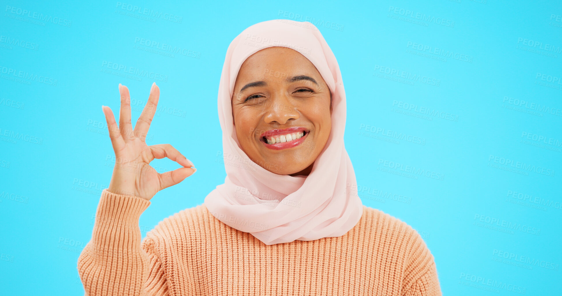 Buy stock photo Muslim woman, ok sign and smile in studio portrait, review and good service by blue background. Islamic person, girl and hijab emoji or happy for agreement with choice, feedback or vote with thanks