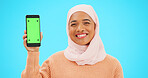 Muslim, phone or green screen and a woman on a blue background in studio holding a display with tracking markers. Islam, mobile contact and an attractive young female showing a screen for marketing
