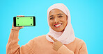 Islam, phone or green screen and a woman on a blue background in studio holding a display with tracking markers. Muslim, mobile contact and an attractive young female showing a screen for marketing