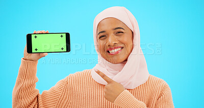 Buy stock photo Islamic woman, green screen phone and studio with point, smile and mockup space by blue background. Muslim person, smartphone and chromakey from choice, promotion and smile for mobile app logo on ux