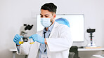 Scientist and research or medical engineer doing experiments to create a cure in a lab while wearing a mask. Healthcare professional working with science equipment and writing notes in a laboratory