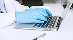 Hands of a scientist in surgical gloves, typing on a laptop in a medical lab. Closeup of a healthcare professional studying, making discovery and innovative breakthrough through DNA and RNA research