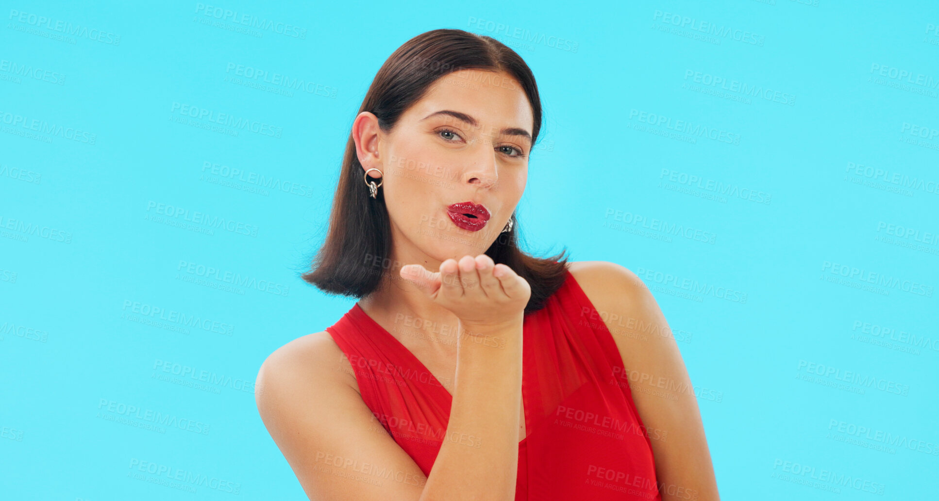 Buy stock photo Woman, blow kiss and studio portrait with makeup, beauty and red dress for date by blue background. Girl, pout lips and emoji with sign language, symbol or icon for love, flirting or valentines day